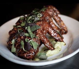 Chicken wings from Detroit's cult-favorite restaurant, Flowers of Vietnam, sit atop creamy cilantro sauce on a white plate