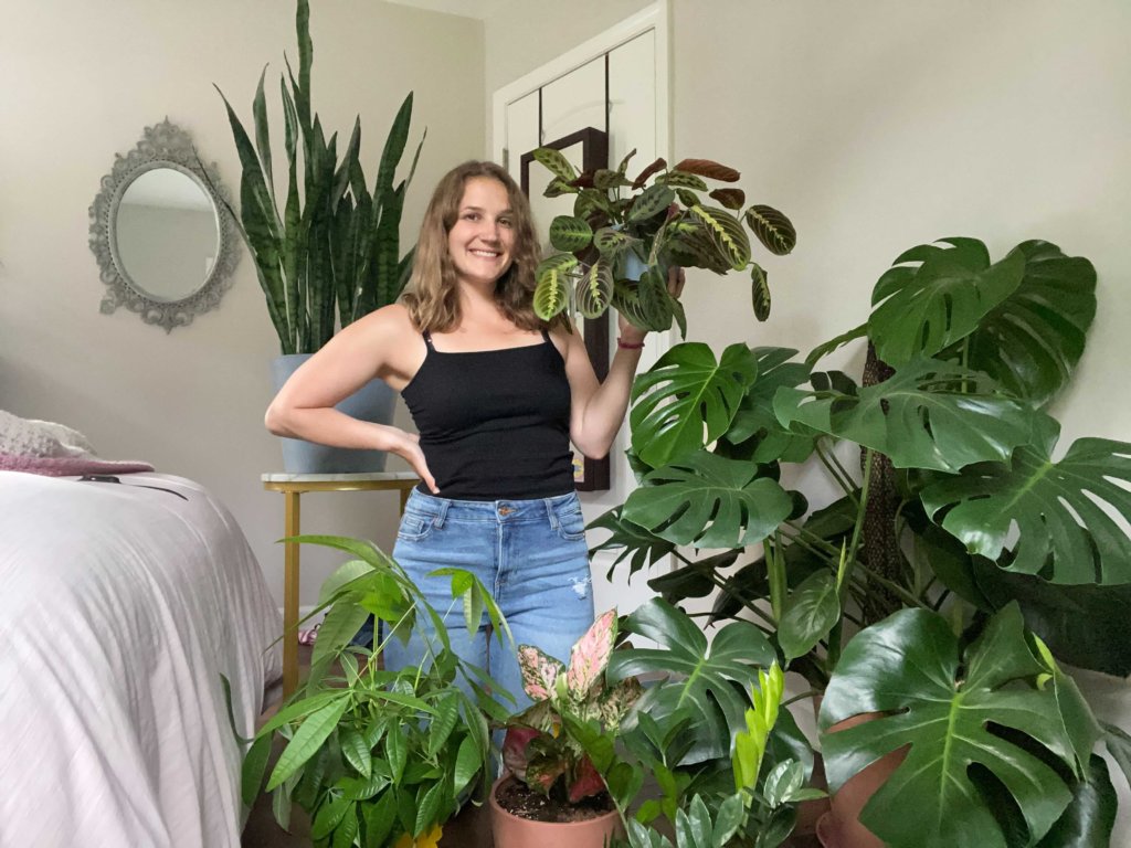 Emma Hondzinski standing in a room filled with plants while holding a plant