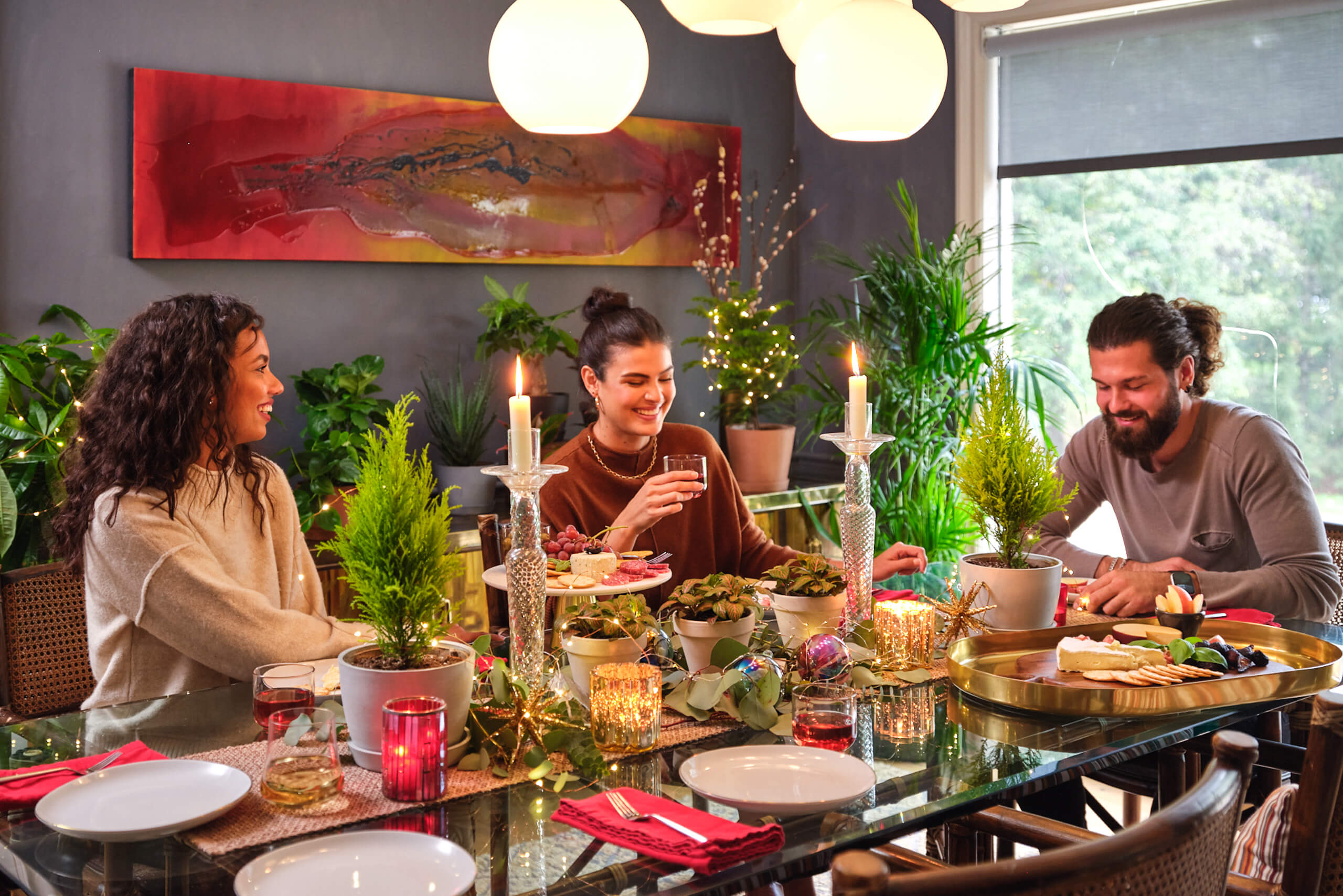 Two women and a man sitting at a dining table with Bloomscape plants surrounded by winter holiday decor