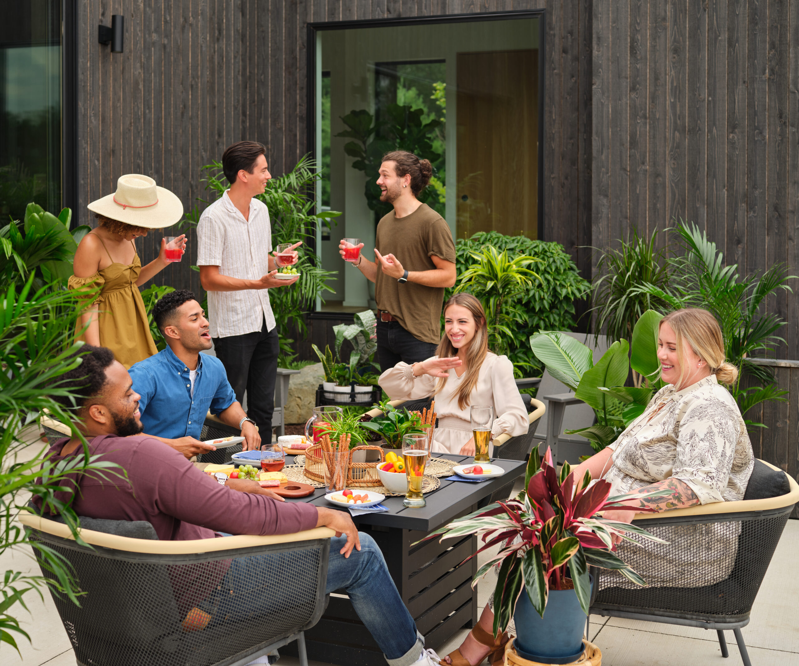 group of people outdoors surrounded by plants and enjoying conversation